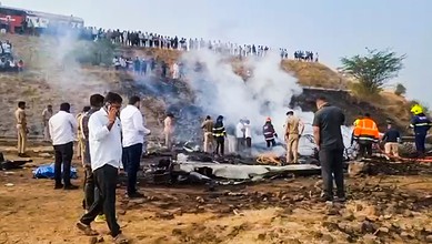 Scene of plane crash in Baramati with officials and onlookers present.