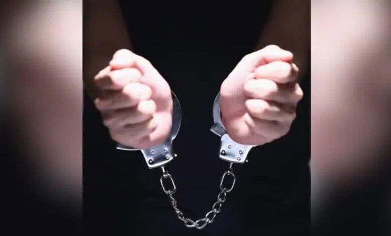 Arrested man in handcuffs, handcuffs linked with chain, close-up image.