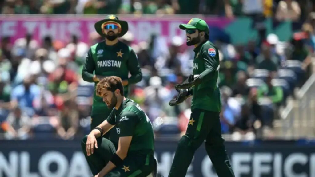 Pakistani cricket players in green uniforms during a match, with a crowd in the background.