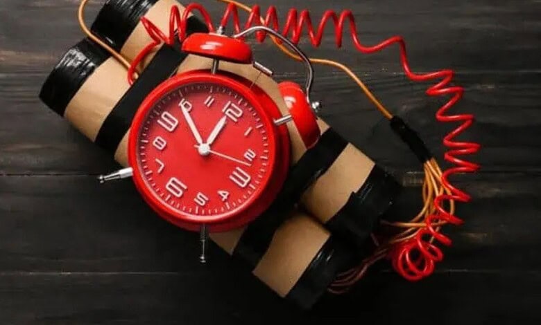Alarm clock with a bomb threat prank, red clock face and dynamite sticks, symbolising danger during.