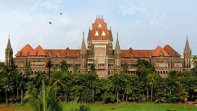 Historic Maharashtra government building with lush greenery and palm trees in front.