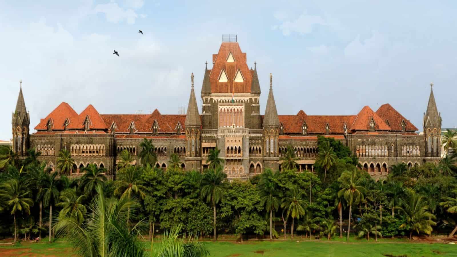 Historic Maharashtra government building with lush greenery and palm trees in front.