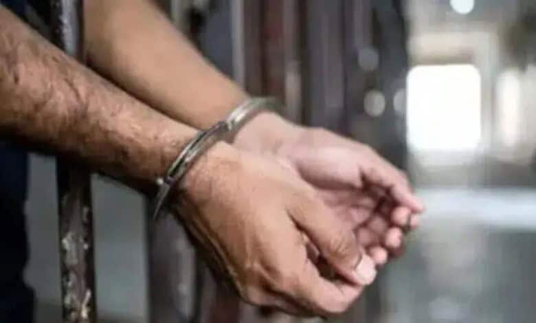 Man in handcuffs sitting in police station corridor.