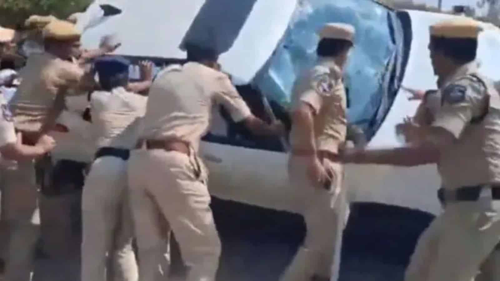 Police officers attempt to control a chaotic scene involving a vehicle during land dispute tensions in Ka.