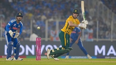 A cricket player in yellow batting for South Africa during a match against India, with the wicketkeeper a.