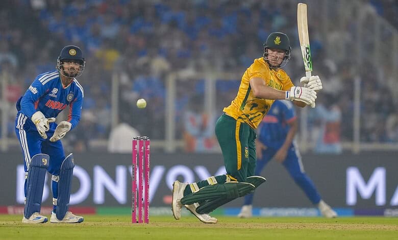 A cricket player in yellow batting for South Africa during a match against India, with the wicketkeeper a.