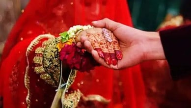 Up of a handshake between bride and groom, highlighting traditional wedding attire and henna designs.