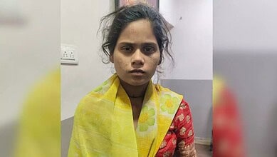 Young girl migrant worker with a serious expression, wearing a yellow and red traditional dress, indoors.