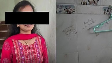 Photo of a young woman in traditional attire with a black bar over her eyes, next to a wall with handwrit.