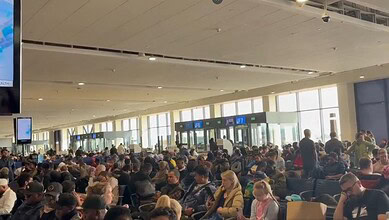 Crowded airport terminal with travelers waiting, reflecting busy travel conditions amid ongoing geopoliti.