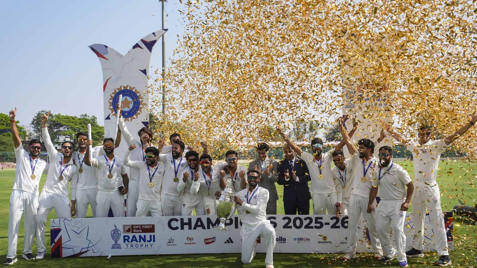 J&K cricket team celebrating their maiden Ranji Trophy victory with players holding medals and a trophy,.