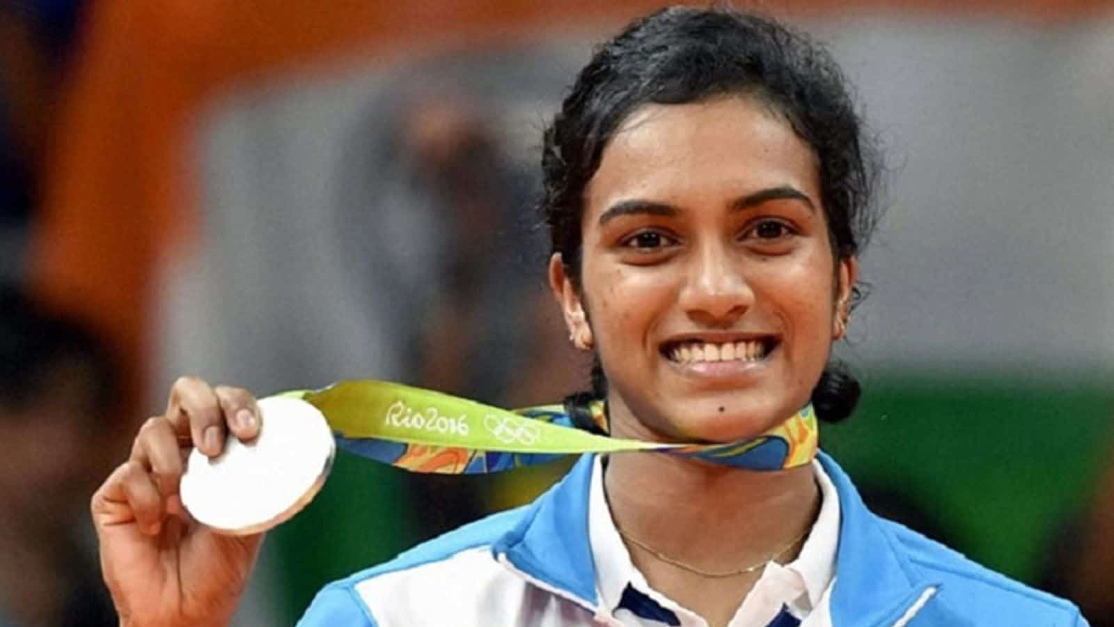 PV Sindhu holding her Olympic silver medal, smiling after winning at Rio 2016.