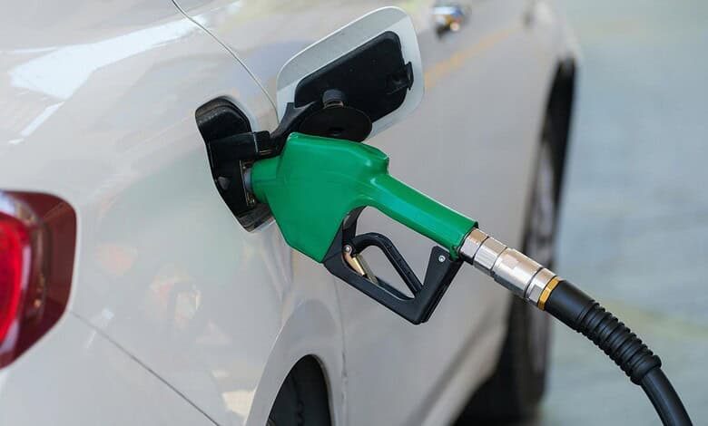 Petrol pump nozzle inserted into a car's fuel tank, promoting E20 ethanol-blended fuel at petrol stations.