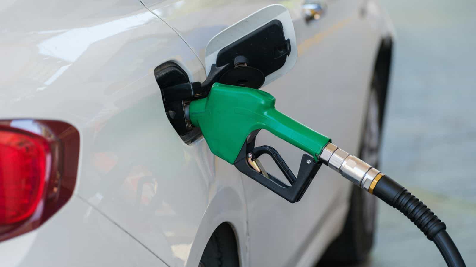 Petrol pump nozzle inserted into a car's fuel tank, promoting E20 ethanol-blended fuel at petrol stations.