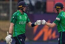 Irish cricket players Lorcan Tucker and teammate fist bump during match against Oman.