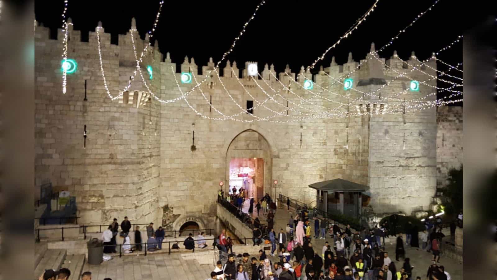 Night view of Jerusalem walls decorated with lights during Ramadan festivities.