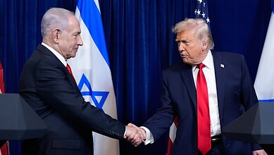 Israeli Prime Minister Benjamin Netanyahu and US President Donald Trump shake hands during a bilateral meeting, with Israeli and US flags in the background.