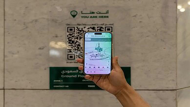 Person scanning a digital wayfinding map on a smartphone at the Grand Mosque and Prophet’s Mosque.