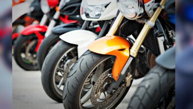Image shows A row of sport motorcycles parked closely together showcasing their front wheels, forks, and fairings