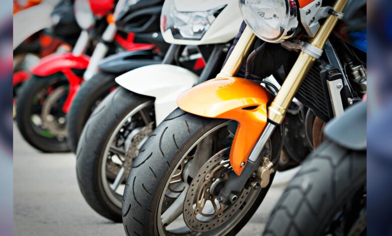 Image shows A row of sport motorcycles parked closely together showcasing their front wheels, forks, and fairings