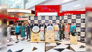 Group of people celebrating at Dubai Duty Free with large prize displays, highlighting a major lottery wi.