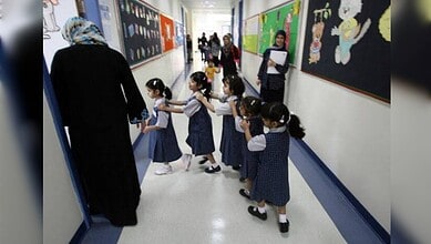 Young children in UAE school hallway with teacher, following new admission age rules.