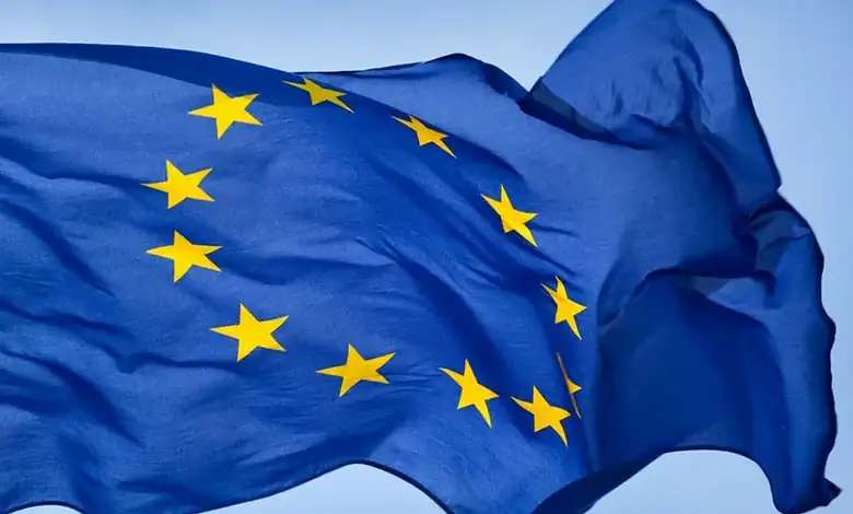 EU flag with yellow stars on a blue background, symbolising unity and cooperation.