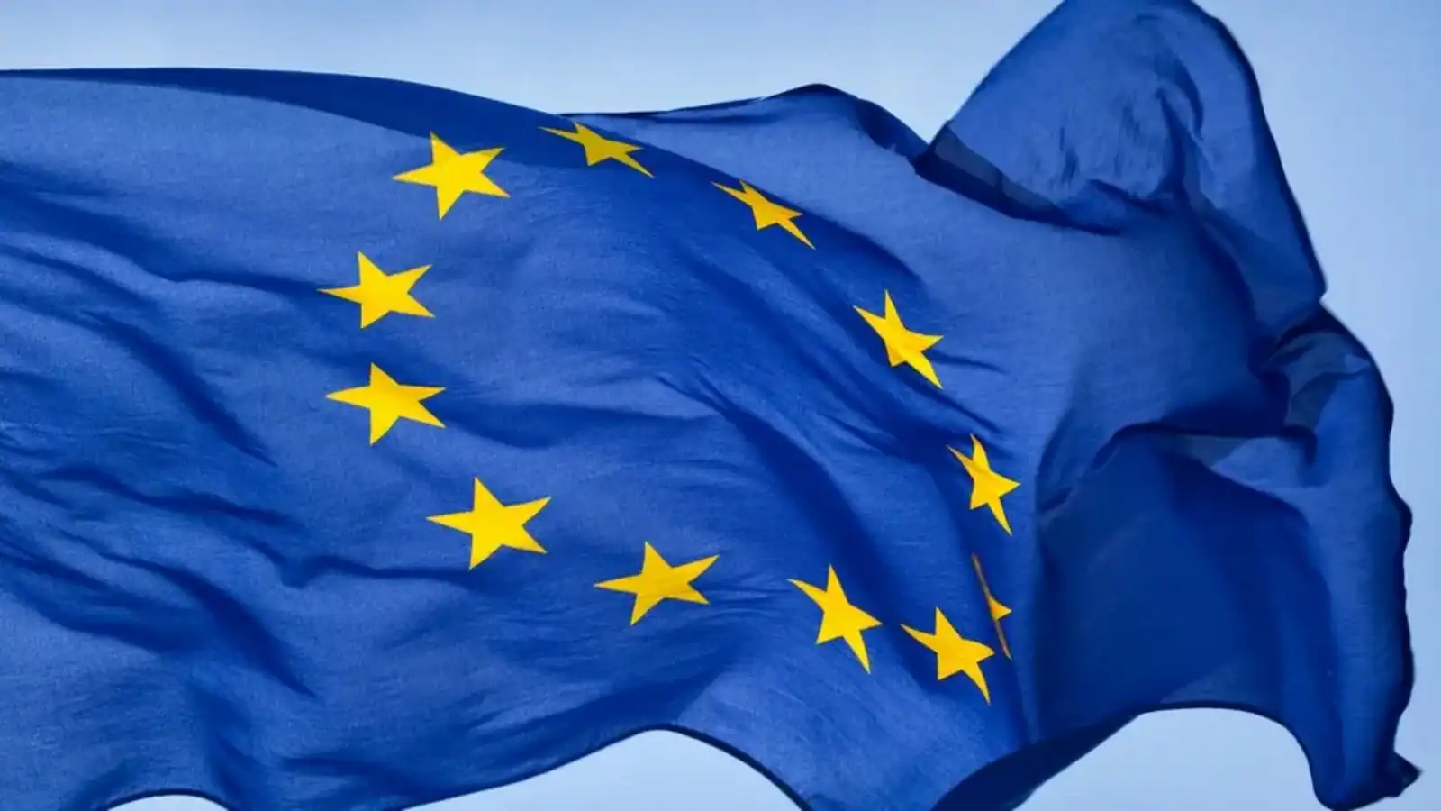 EU flag with yellow stars on a blue background, symbolising unity and cooperation.