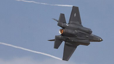 Fighter jet flying at high speed, leaving contrails in the sky.