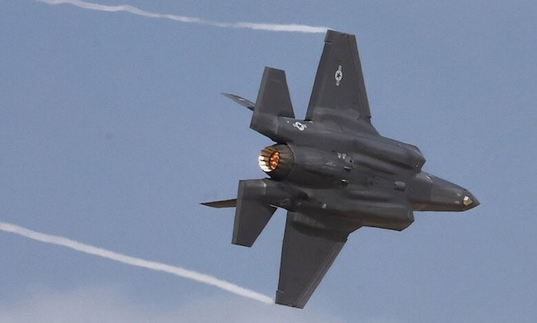 Fighter jet flying at high speed, leaving contrails in the sky.
