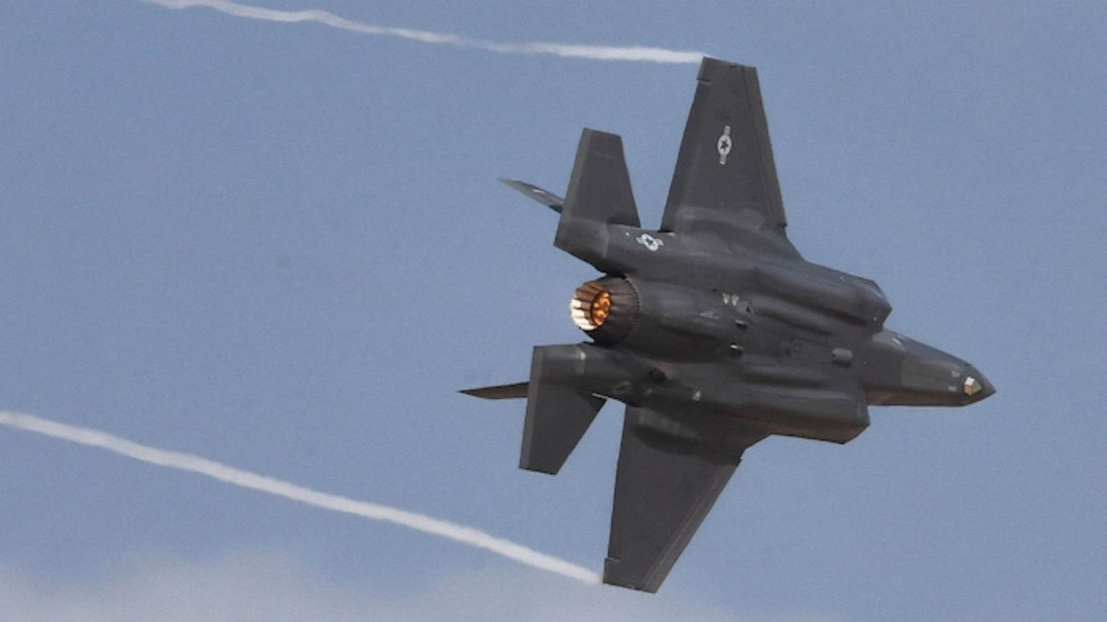 Fighter jet flying at high speed, leaving contrails in the sky.