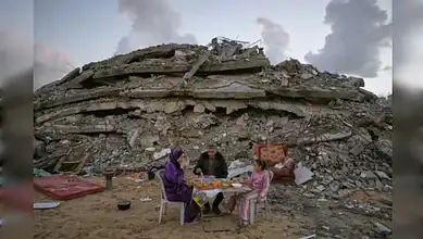 Ruins in Gaza after airstrike; family gathers amid destruction.