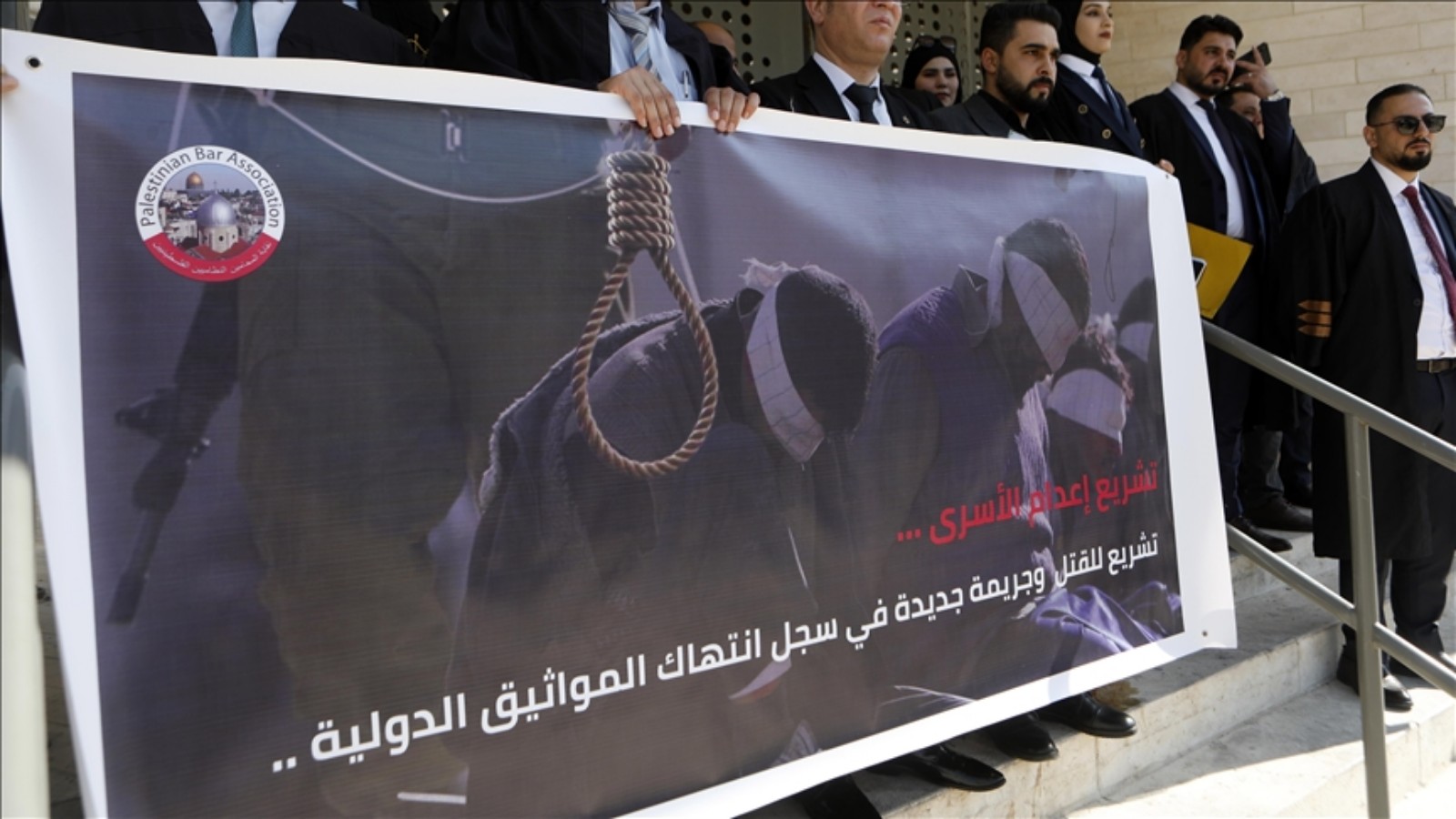 Lawyers in Hebron hold a banner depicting a noose and blindfolded detainees during a protest against a proposed death penalty law.