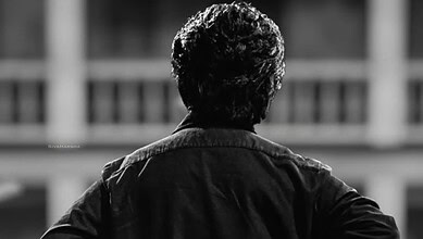 Black and white image of an elderly male actor with curly hair facing away.