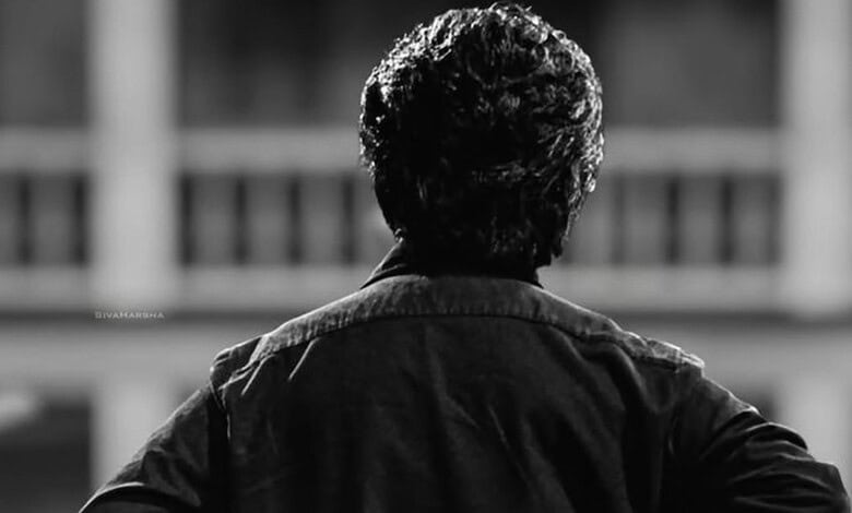 Black and white image of an elderly male actor with curly hair facing away.