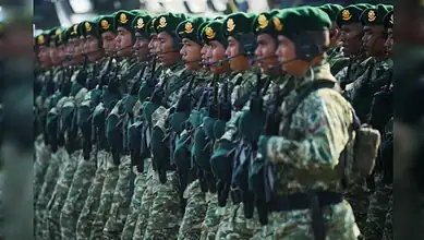 Indonesian soldiers in green berets march in formation during a military ceremony in Jakarta.
