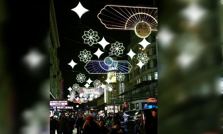Colourful illuminated street decorations with stars and umbrellas in a lively urban setting.