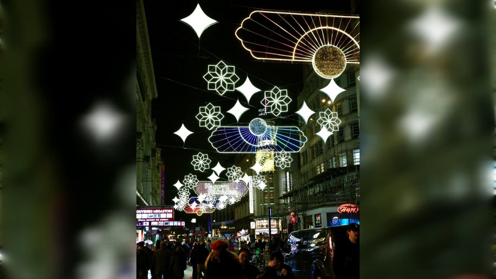 Colourful illuminated street decorations with stars and umbrellas in a lively urban setting.