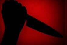Image shows A dramatic silhouette of a hand gripping a knife against a glowing red background,