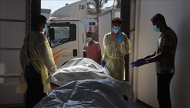 Medical team handling a body on a stretcher at a hospital or morgue.