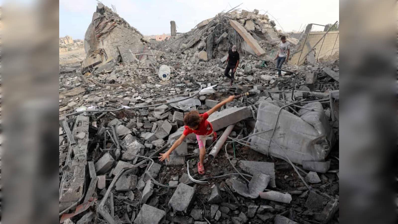 Palestinian girl walks across debris as civilians inspect the rubble of a building destroyed in an Israeli air strike in Bureij refugee camp, central Gaza Strip.