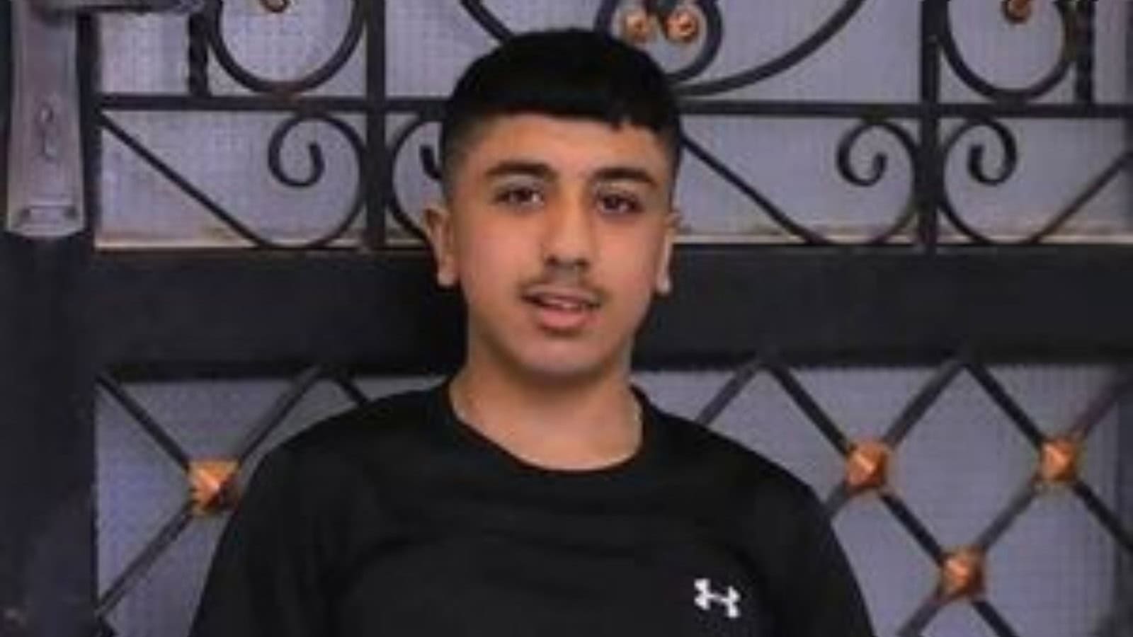 The image of Palestinian teenager Jad Jadallah standing in front of a metal gate.