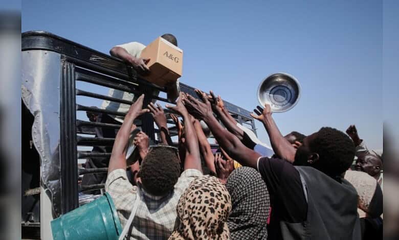 Aid workers and civilians reach for supplies from a drone strike-hit convoy in Sudan.