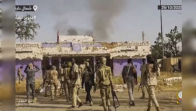 An image showing armed personnel and smoke rising from buildings amid ongoing violence in Sudan.