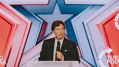 Podcast host Tucker Carlson speaks at a podium during Turning Point’s AmericaFest conference in Phoenix, Arizona.