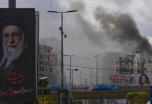 A portrait of Iran's late Supreme Leader Ayatollah Ali Khamenei, left, is seen, as smoke rises following an Israeli airstrike in Dahiyeh, Beirut's southern suburbs, Lebanon