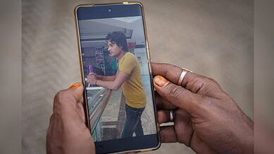 Woman with yellow shirt using smartphone at train station platform.