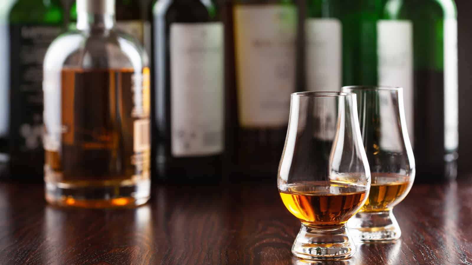 Alcoholic drinks served in glasses on a bar counter with bottles behind.