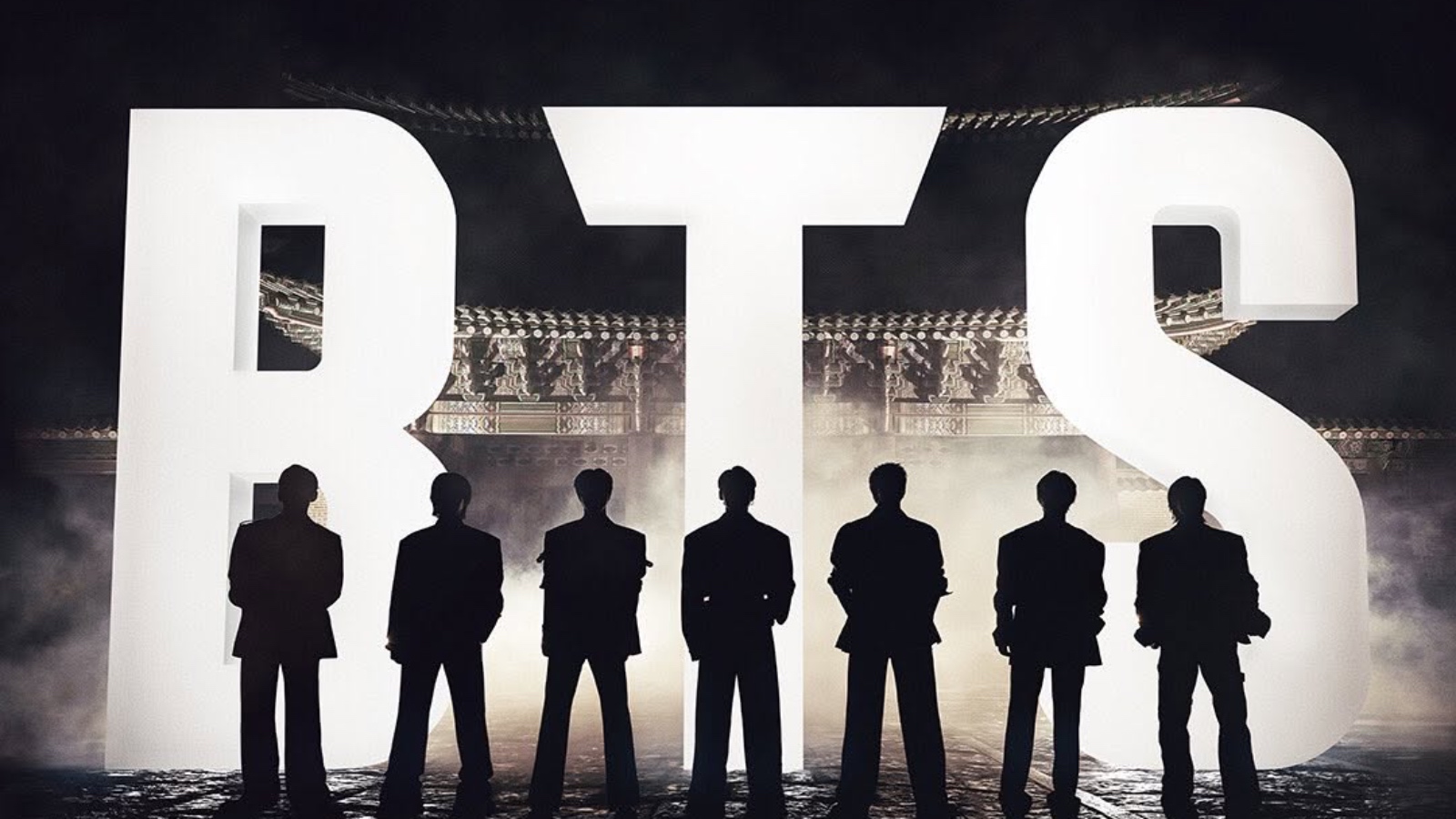 K-pop stars standing on stage during a comeback event, silhouetted against bright lights.