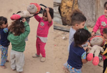 Children in Gaza act out a funeral scene while they play with dolls